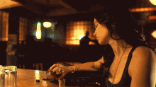 a woman sitting at a bar with a bottle of jack daniels on the counter