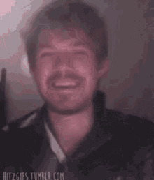 a blurry picture of a man with a mustache making a funny face