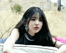 a woman with a piercing in her lip is wearing a black top and silver earrings