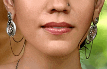 a close up of a woman 's face with earrings and a nose ring