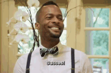 a man wearing a bow tie and suspenders is smiling .