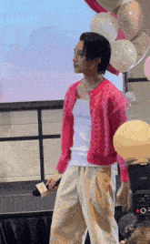 a man in a pink cardigan is standing on a stage holding a microphone ..