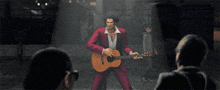 a man in a red suit is holding a guitar and singing