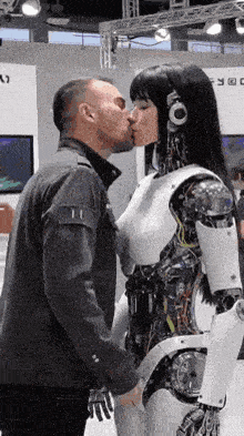 a man is kissing a robotic woman in a futuristic outfit .