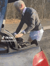 a man is putting something in the back of a car with a tiktok watermark on the bottom