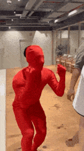 a man in a red costume is dancing in a room .
