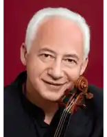 a man with white hair is holding a violin