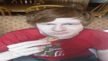 a boy wearing a morelos shirt holds a cookie in his hand