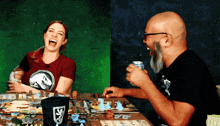 a man and a woman are playing a board game and the woman is wearing a t-shirt with a dinosaur on it