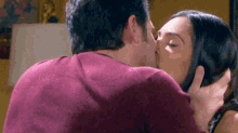 a man and a woman are kissing in a room