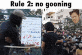 a man holding a sign that says " rule 2 : no gooning "