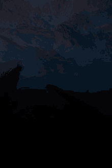 a dark landscape with mountains in the background at night
