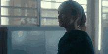 a woman in a black shirt is standing in front of a window .