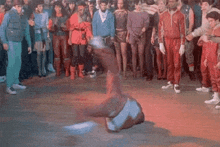 a man is doing a trick on the floor in front of a crowd .