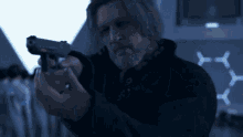 a man with a beard is pointing a gun at the camera .