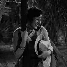 a black and white photo of a woman holding a hat in her hand