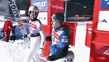 two skiers are standing in front of a building that says hylo on it