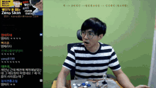 a man in a striped shirt sits in front of a screen that says zero skin on it