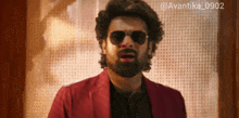 a man with a beard wearing sunglasses and a red jacket with the hashtag avantika0902