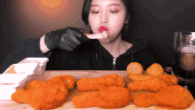 a woman wearing black gloves eating fried chicken