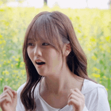 a woman in a white shirt stands in a field of yellow flowers