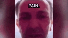 a close up of a man 's face with the words pain written on his forehead