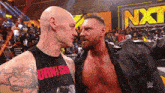 two wrestlers are facing each other in front of a nxt banner