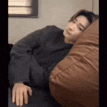 a man is laying on a couch with his head on a pillow .