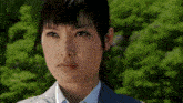 a close up of a woman 's face in front of trees .