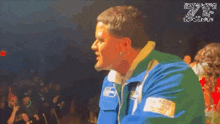 a man in a blue and green jacket stands in front of a crowd with the number 20 on the bottom