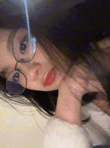 a woman wearing glasses is laying down with her hand on her face