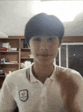 a young man wearing a white shirt with a badge on the front that says ' basketball '