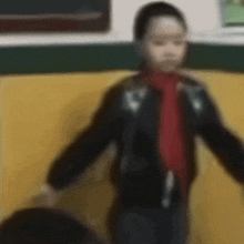 a blurry picture of a young boy wearing a black jacket and a red tie