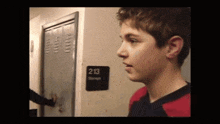 a young boy stands in front of a locker with a sign that says 213 storage