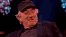 a man wearing a hat is laughing and clapping his hands .