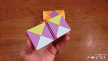 a person is playing with a colorful origami cube made by animatica