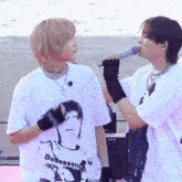 a man singing into a microphone next to another man wearing a t-shirt that says beessen