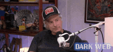 a man in a hat is sitting in front of a microphone in a room .