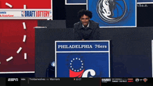 a man stands behind a podium that says draft lottery on it