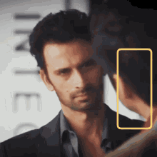 a man in a suit is looking at himself in a mirror with a yellow frame around him