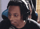a man with dreadlocks is wearing headphones and smiling at the camera .