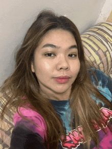 a woman laying on a couch wearing a tie dye shirt that says ' nirvana '