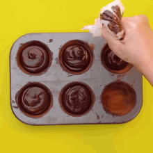 a tray of chocolate cupcakes is being decorated with chocolate frosting