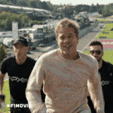 a man wearing a pink sweater is smiling while walking with two other men