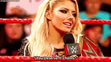 a woman is holding a microphone in a wrestling ring and saying `` you deserve it '' .