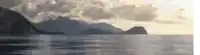 a large body of water surrounded by mountains and clouds