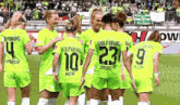 a group of female soccer players are huddled together with one wearing the number 23 on her back