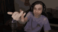 a man wearing headphones and a purple shirt is sitting in a chair holding a bottle of water .
