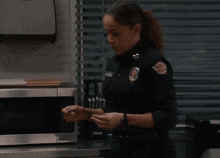 a woman in a police uniform is standing in front of a silver microwave