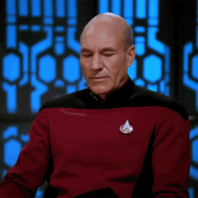 Animated meme of Sir Patrick Stewart as Captain Jean-Luc Picard in Star Trek: The Next Generation. He is sitting at a desk with a disgruntedled look and slowly puts his hand over his face and rubs his forehead. Facepalming.